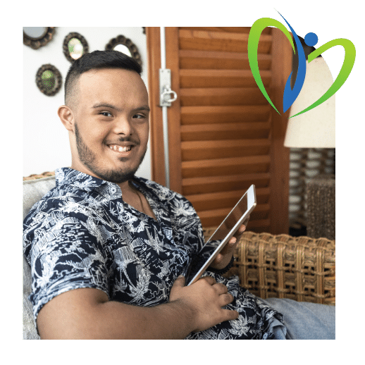 Disabled man with down syndrome holding iPad and smiling at camera while sitting on couch